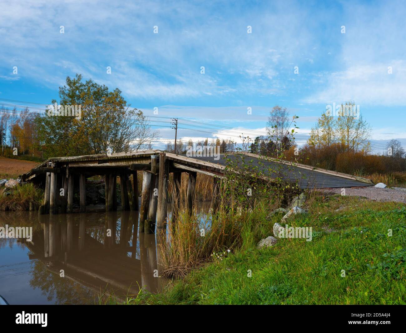 Sipoo/Finland - OCTOBER 12, 2020: A beautiful rural scene with an old wooden bridge casting reflections on the calm river surface. Stock Photo