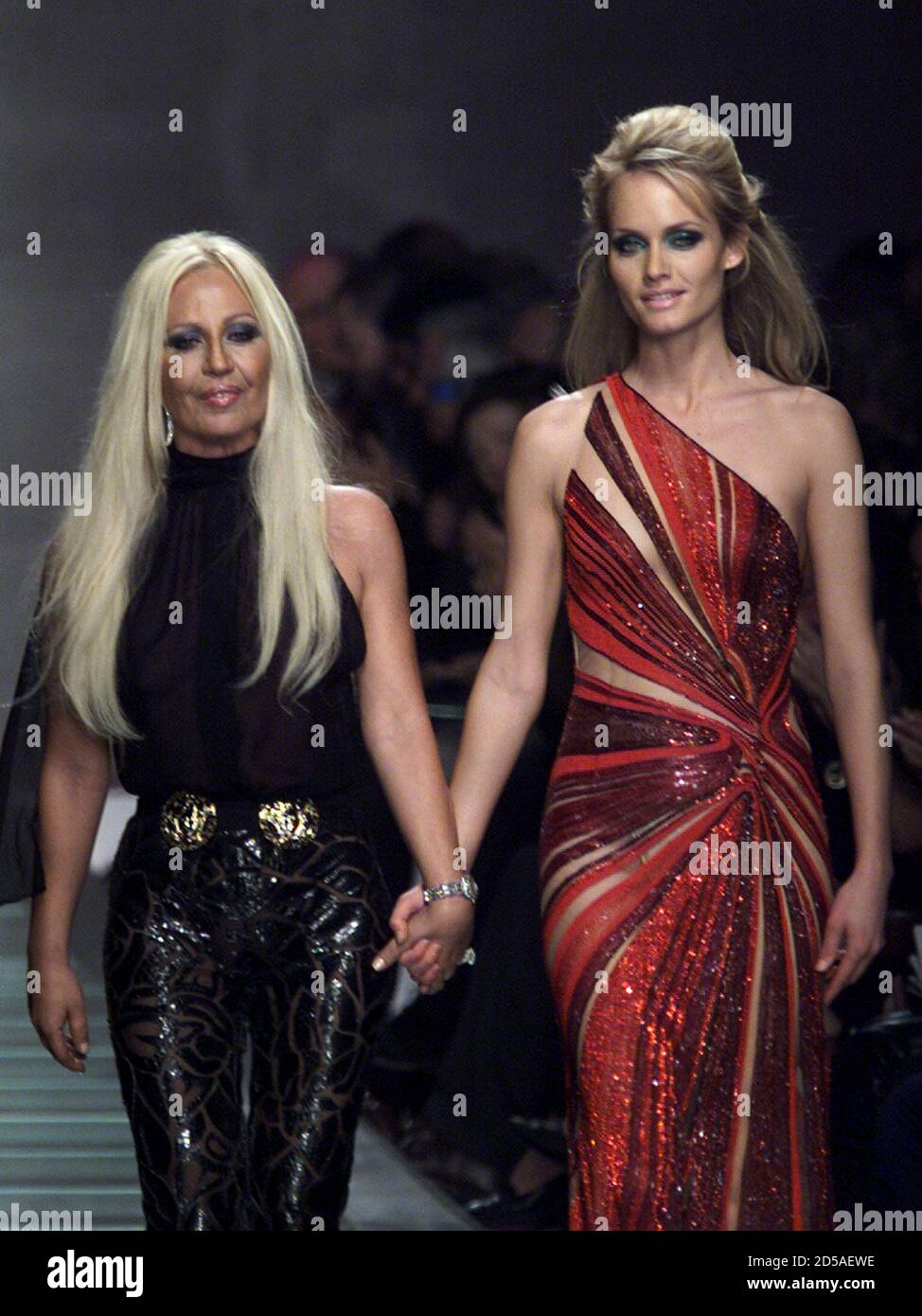 Italian designer Donatella Versace acknowledges the applause on the catwalk  with a model at the end of Gianni Versace's Autumn/Winter 2000/2001  ready-to-wear women's collection in Milan, February 25. The Milan fashion  show
