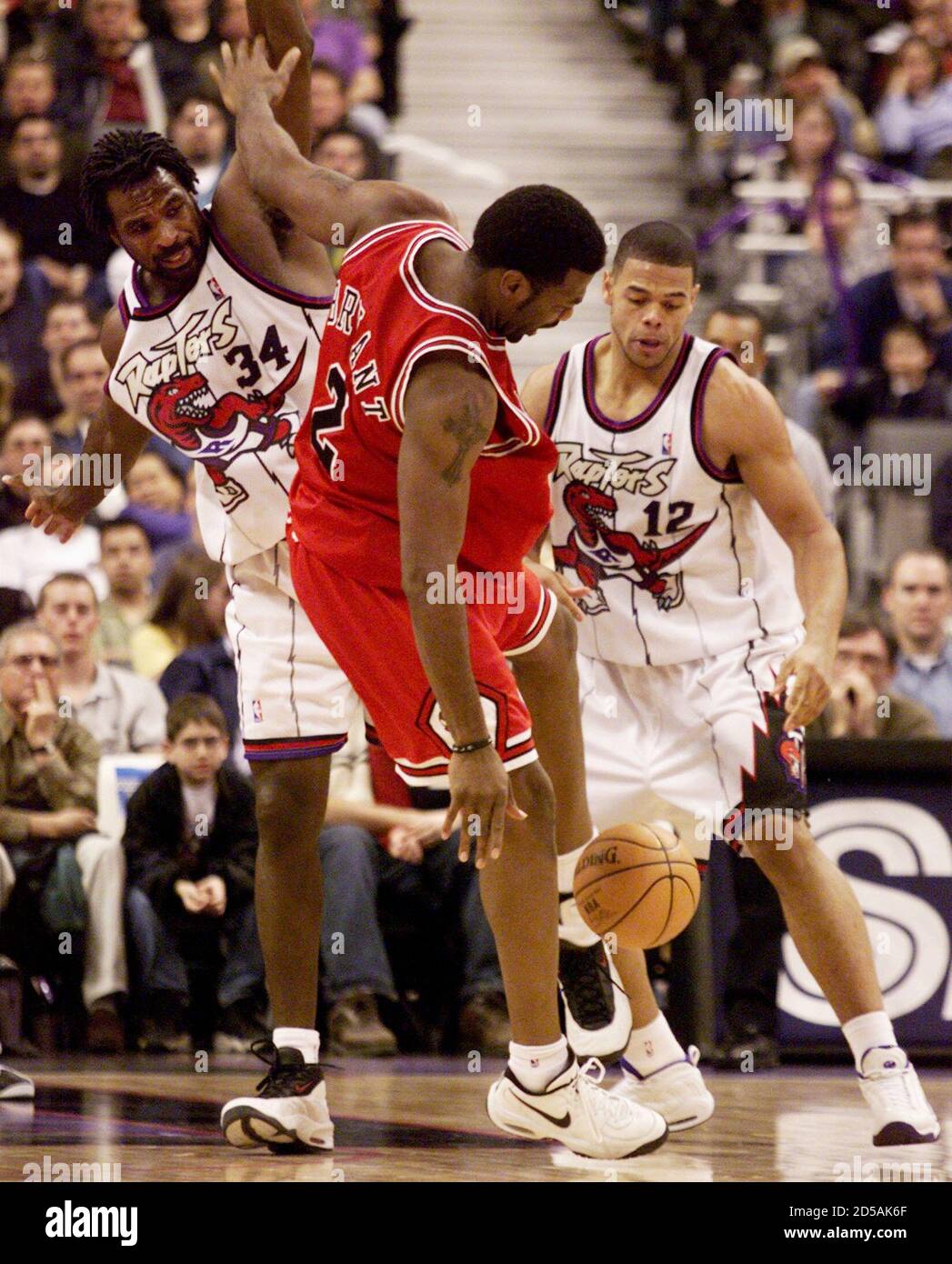 Toronto Raptors forward Charles Oakley (L) blocks the shot of Chicago Bulls  forward Mark Bryant (C) while Raptors forward John Thomas goes for the  loose ball during the second half of their