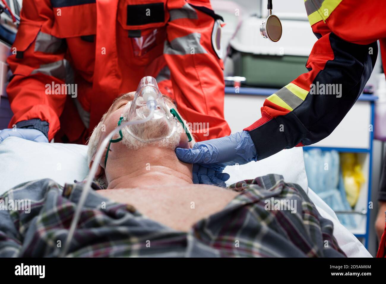 Selective focus of paramedic in latex glove checking pulse of senior