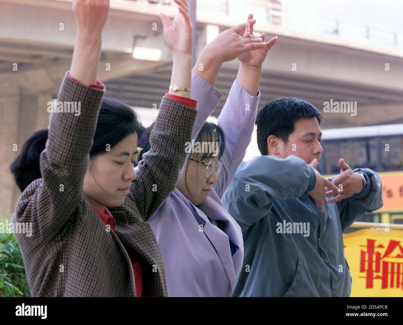 Three followers of China's banned Falun Gong spiritual movement (from L to R) Zhao Chen, Feng Lili and Huang Yun practice qigong during a protest in Hong Kong December 28. The three U.S.-passport holders, detained on December 15 for 'disrupting social order' after they travelled to Shenzhen in southern China, were released on Monday. A Chinese court earlier sentenced four leaders of the movement to up to 18 years in prison on charges ranging form stealing state secrets to causing deaths.  BY/TAN Stock Photo