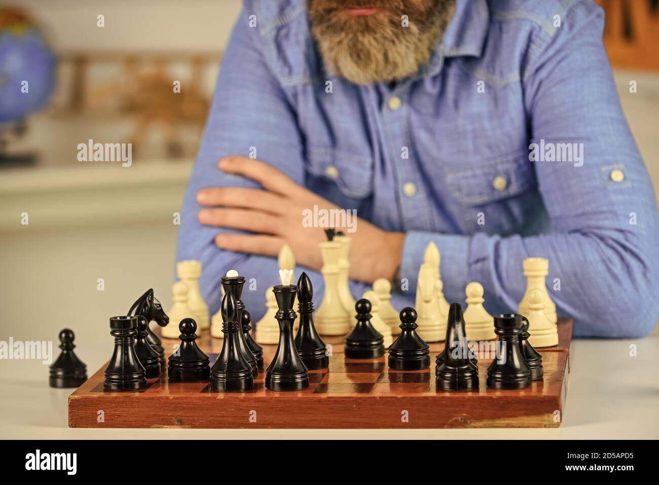 chess figures on wooden board. Focused school teacher. thinking of attacking and capturing opponent chess pieces. thinking of next move. bearded man training for chess competition. Stock Photo