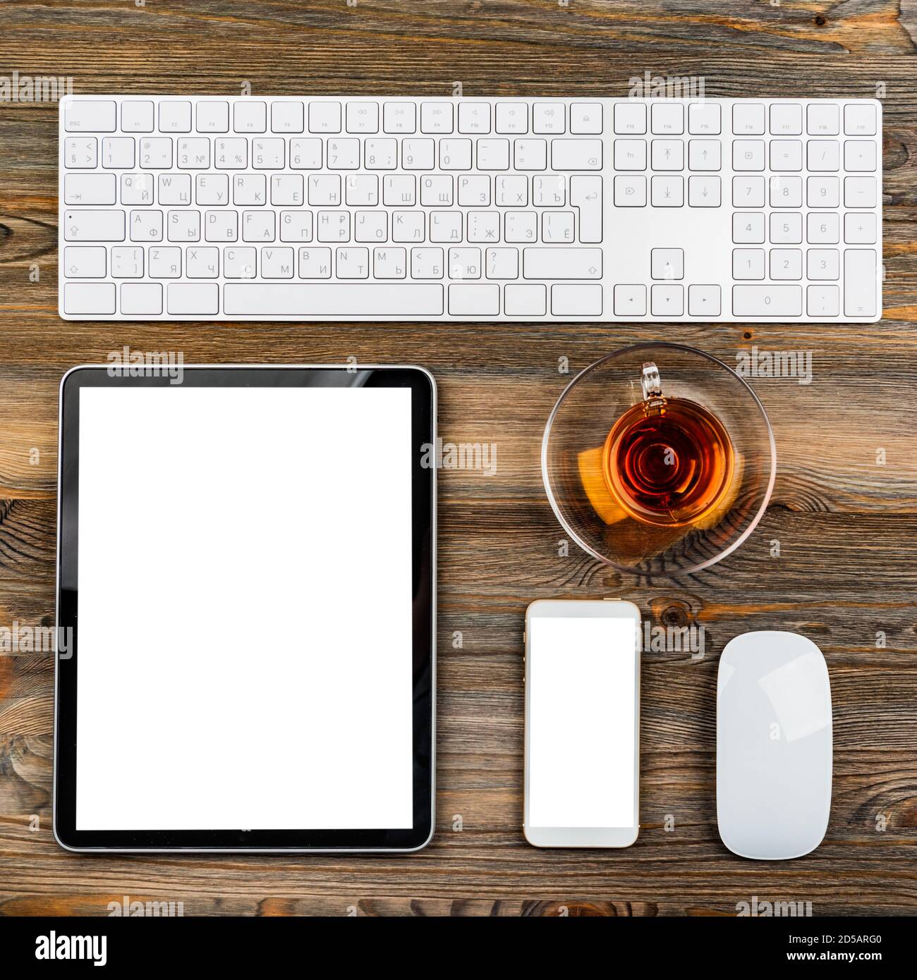 office table with computer keyboard, mouse, cup of tea, tablet pc and smartphone Stock Photo