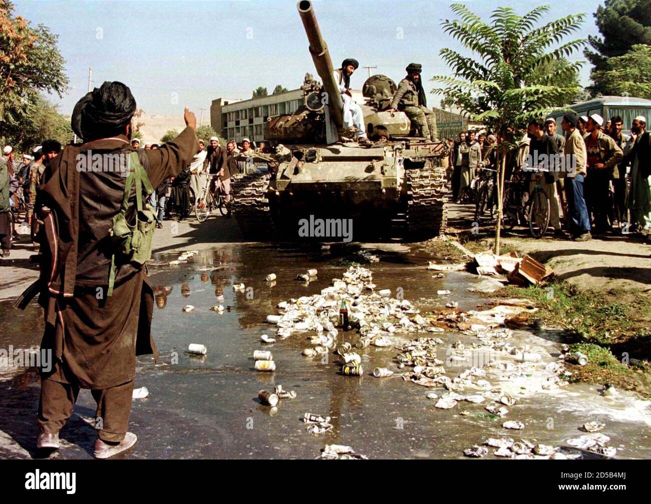 An Afghan Islamic Taliban fighter leads a heavy battle tank over cans of beer to demonstrate their loathing of alcohol, October 24. The tank drove over the cans a dozen times, spraying beer over bystanders. The Taliban did not say where the beer had come from, saying only it had been seized. Stock Photo