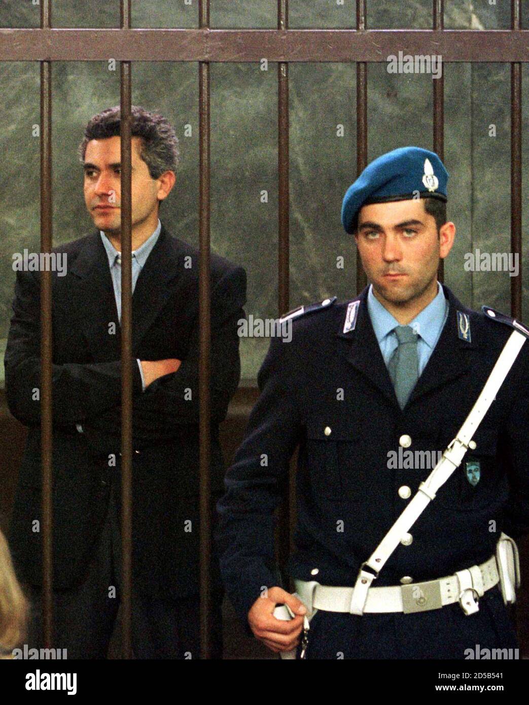 Alleged contract killer Benedetto Ceraulo (L) is guarded at the start of the trial of Patrizia Reggiani, the ex-wife of murdered fashion mogul Maurizio Gucci, May 11. Gucci, the last grandson of Guccio Gucci, the founder of the world famous fashion empire, was gunned down in central Milan in March 1995 by a contract killer. The trial was immediately adjourned on its opening day after defence lawyers joined a national strike by Italy's legal profession. Stock Photo