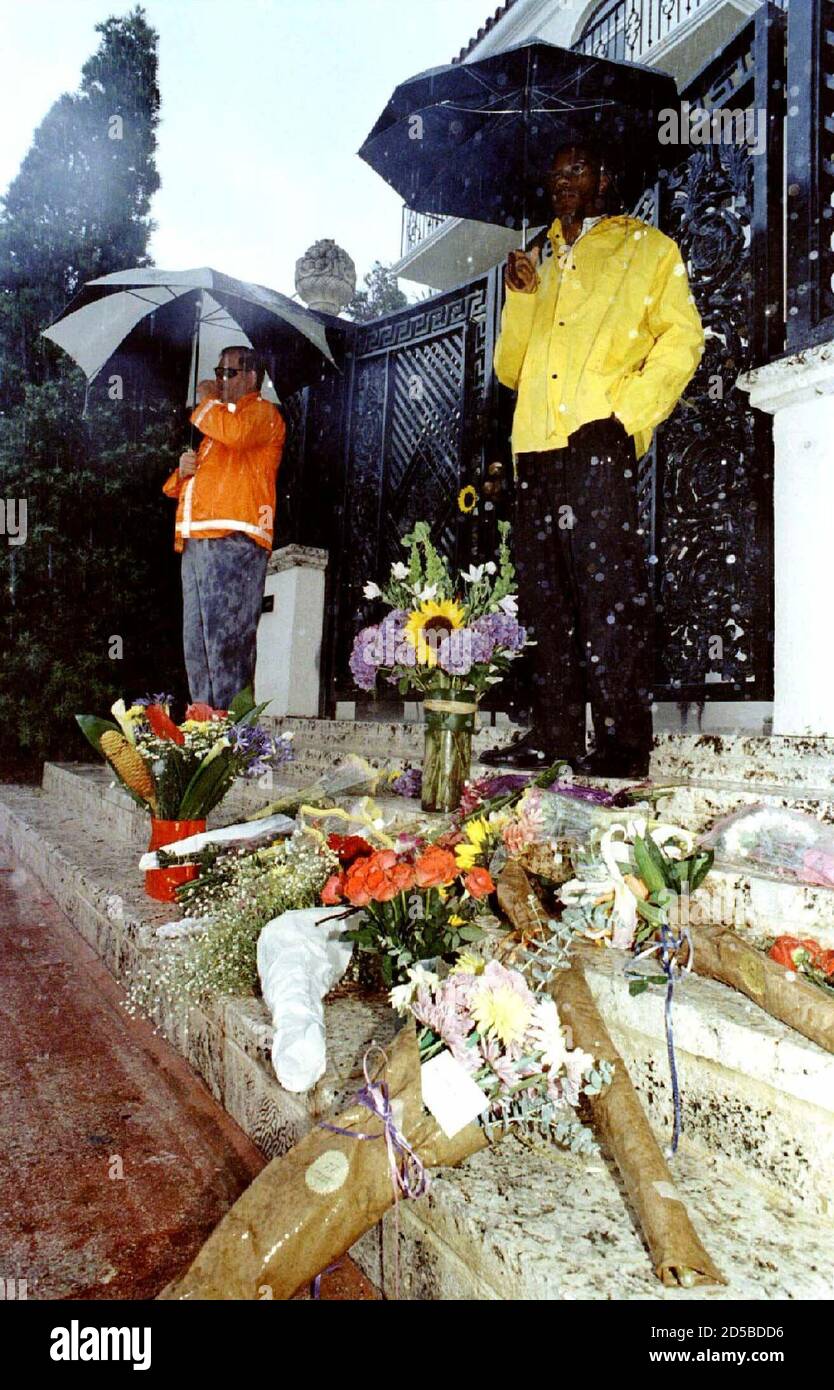 Guards Stand In The Pouring Rain Outside The Front Gate Of Gianni Versace S Miami Beach Mansion July 15 As Flowers From Well Wishers Lay On The Steps Where The World Famous Fashion