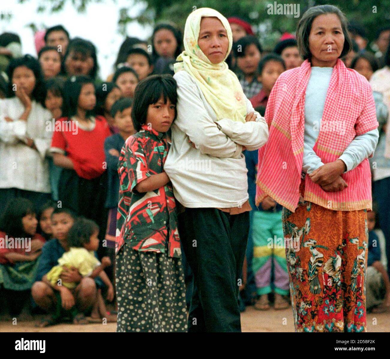 Mea Son (R), widow of the late Khmer Rouge leader Pol Pot,  watches fellow Cambodian refugees leaving Phu Noi refugee camp at the Thai-Cambodian border, 500 km north east of Bangkok January 12. The child at left has been identified by the Thai military as the teenaged daughter of the reviled dictator. The woman in the centre is unidentified. About 400 refugees, the first group of Khmer Rouge dependents,  returned to Cambodia [after their leaders Khieu Samphan and Nuon Chea defected to the Phnom Penh government last month.] Stock Photo