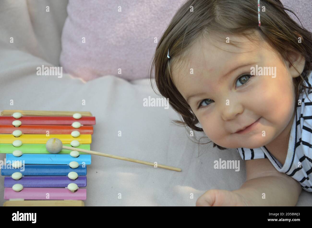 Cute blond child playing with xylophone at home. Creativity and education concept. Stock Photo