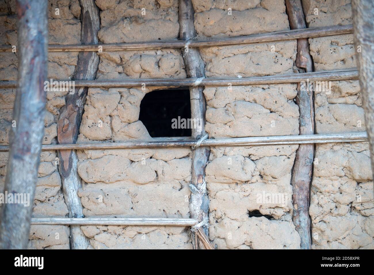 Hole used like a window in Rural home made of sticks and mud with thatched house in Tanzania. Poverty of developing nation and culture of Swahili Stock Photo