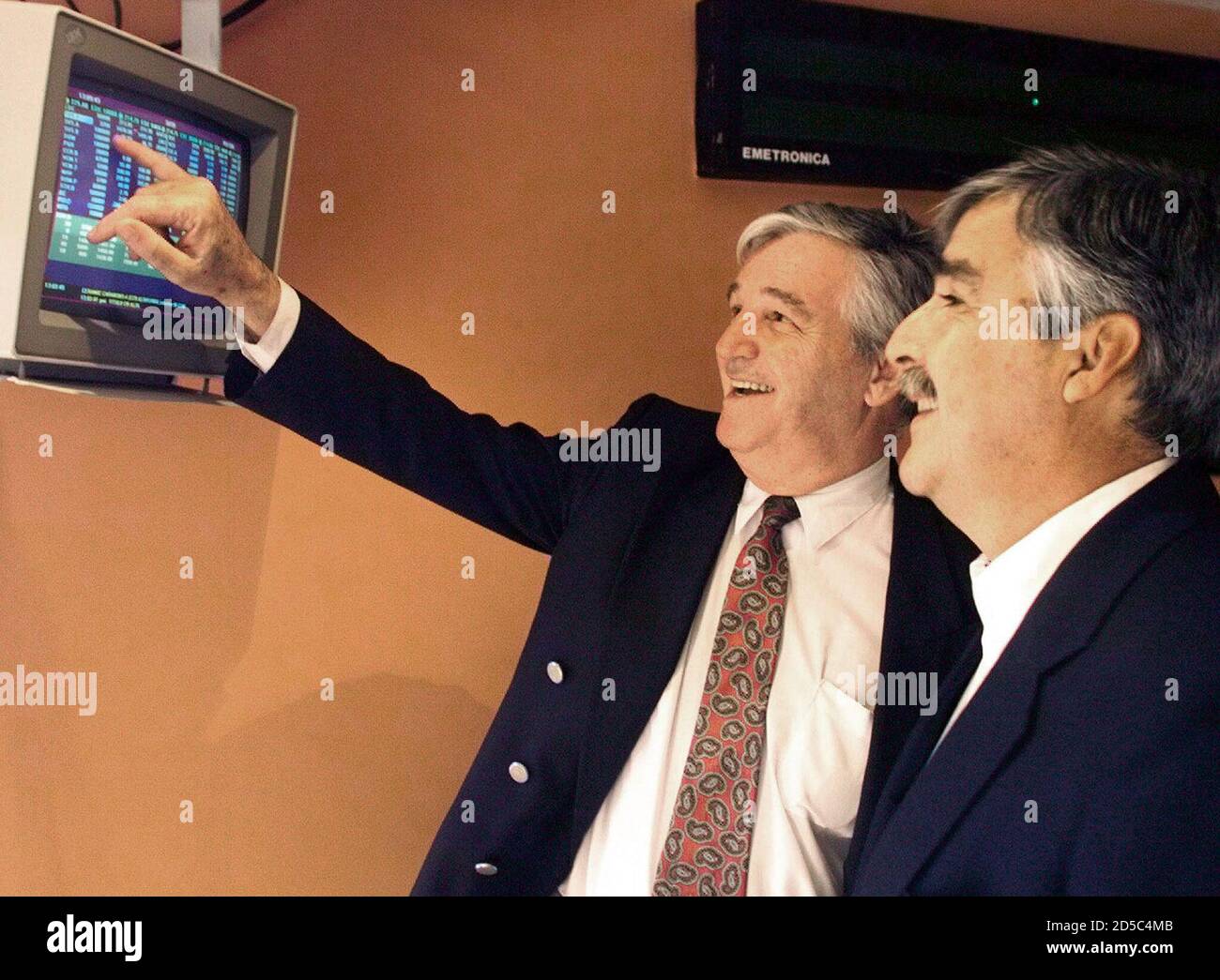 Venezuelan investors, Alejandro Garcia (L) and Carlos de Seda, smile while  watching on a screen at the Caracas Stock Exchange, their utility stocks  rise to record levels December 8. Analysts attributed the