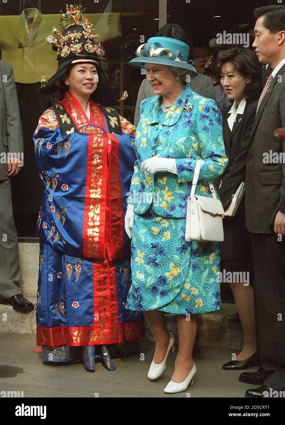 Britain's Queen Elizabeth II passes a woman dressed in a royal Korean  costume as the visiting monarch walks around the art and antique district  of Insadong in Seoul April 20. The queen,