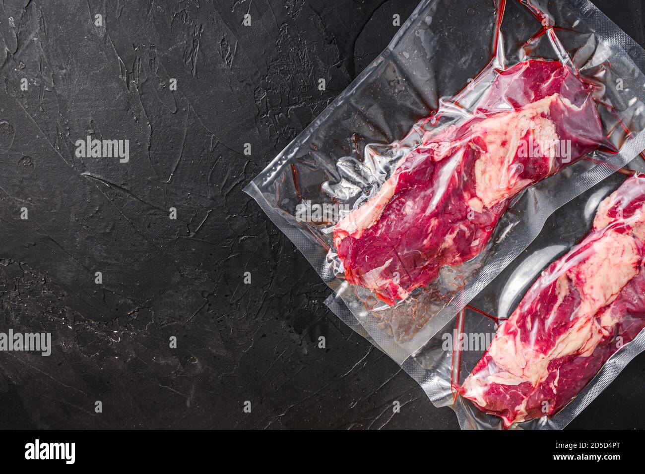 Chuck Tenders beef steak in vacuum sealed bag on black textured ...