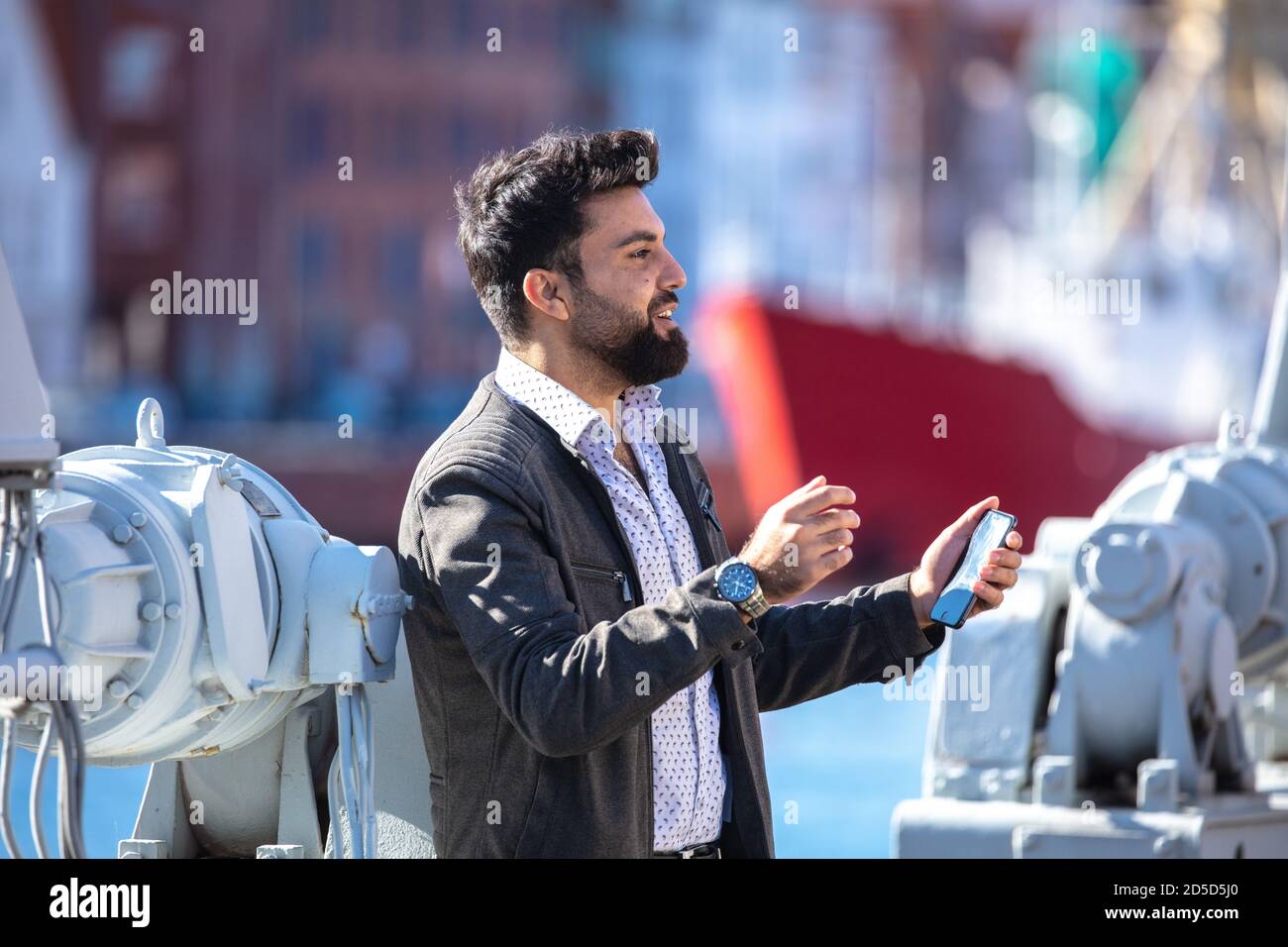 Mann steht fröhlich am Hafen, Smartphone in der Hand Stock Photo
