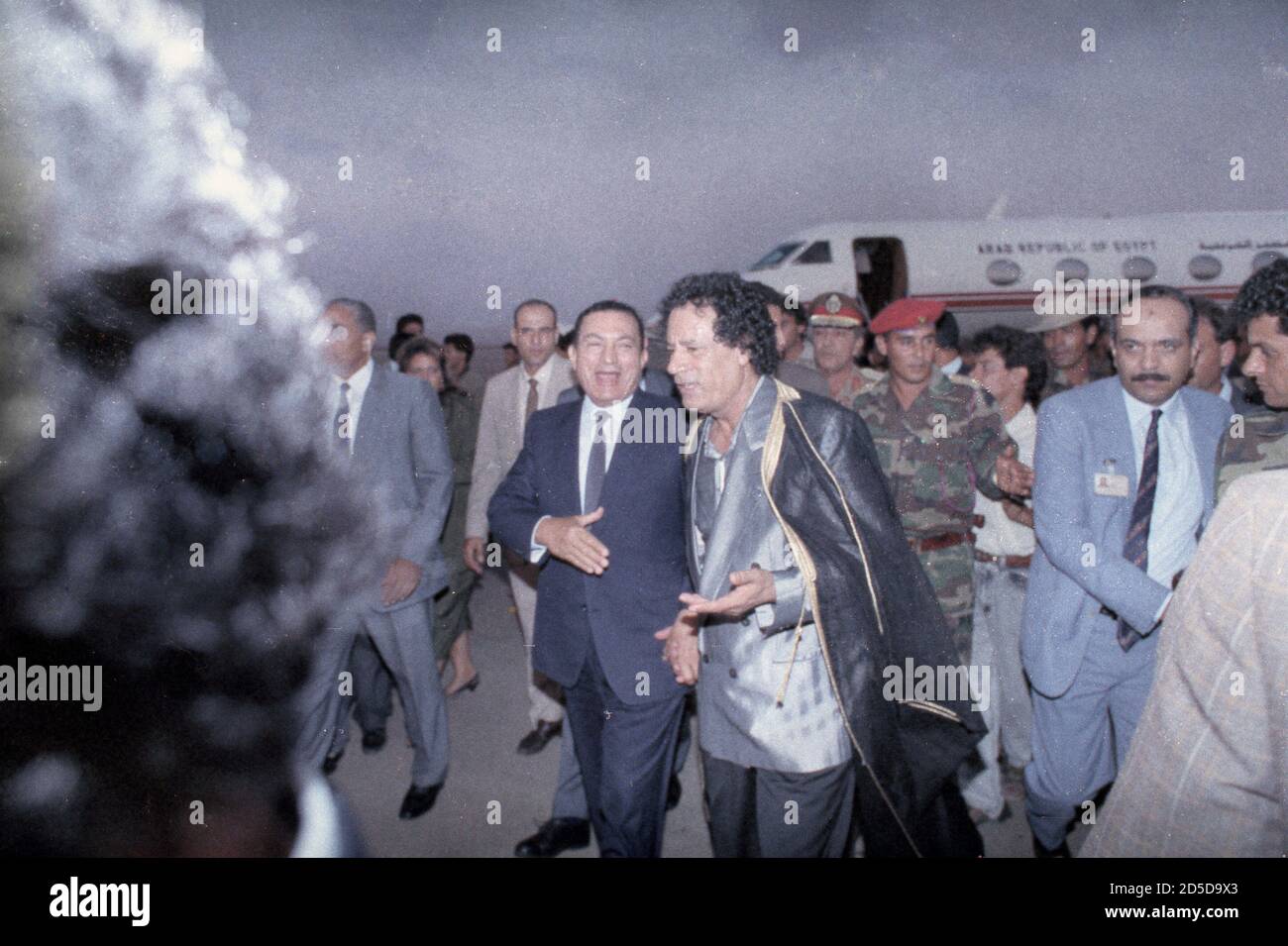 Egyptian President Hosni Mubarak (L) jokes with Libyan leader Colonel Muammar Gaddafi upon his arrival at Benghazi airport August 27, 1991. Leaders and representatives from around the world are gathering in the city for the inauguration of the Great Man Made River project, designed to provide water for the north of the country at a cost of over $20 billion.   REUTERS/Jon Bainbridge   BEST QUALITY AVAILABLE Stock Photo