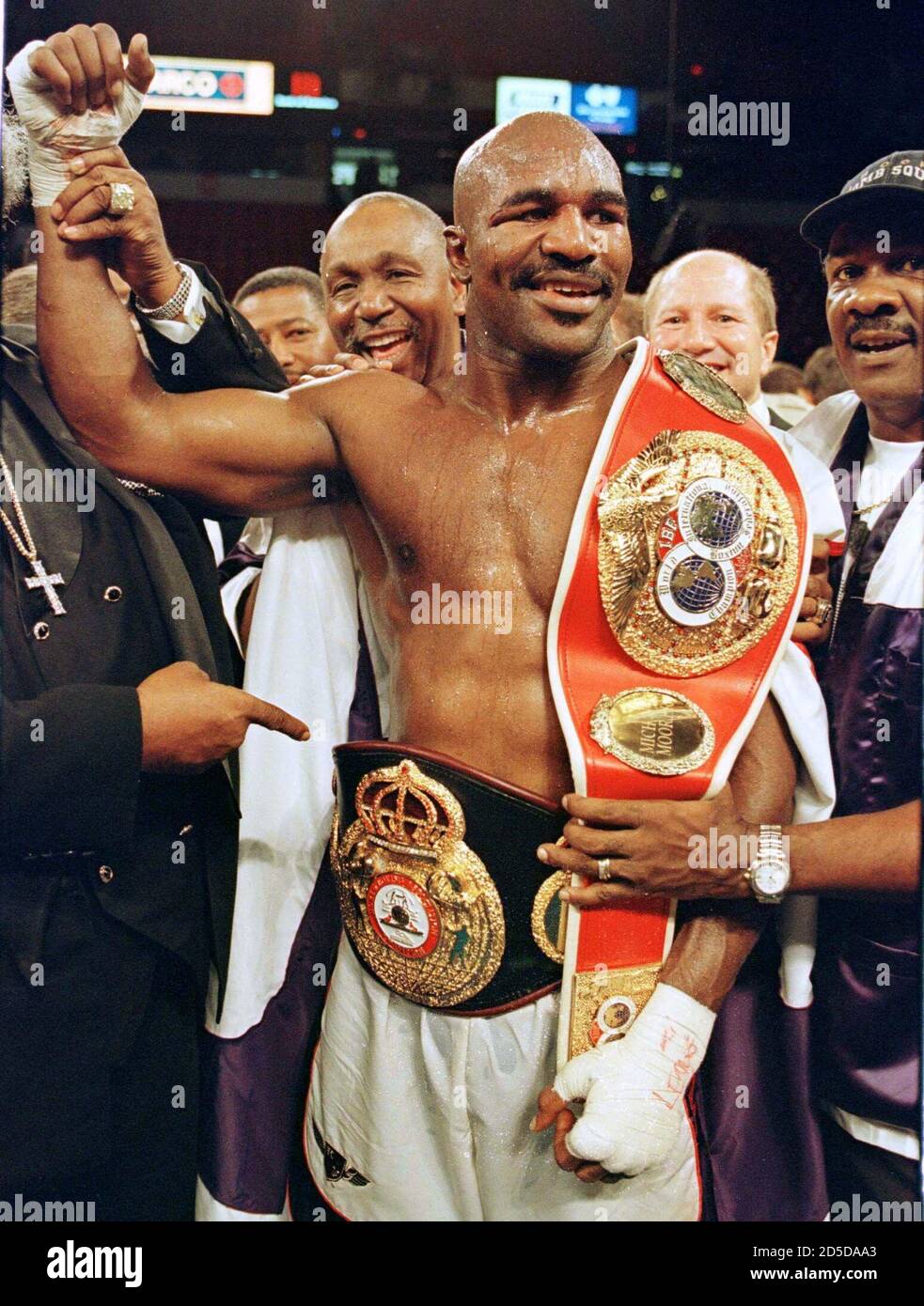 Heavyweight Evander Holyfield(C) holds the IBF ad WBA championship belts  following his defeat of IBF champion Michael Moorer November 8. Holyfield  won the IBF title and retained his WBA championship when the