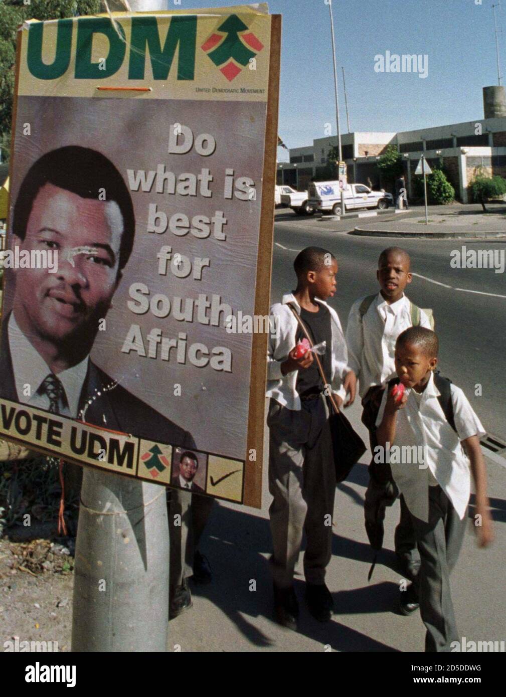School children pass beneath an election poster as special ...
