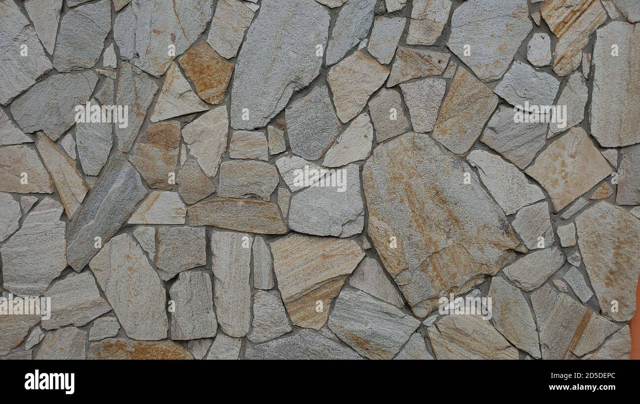 Brick wall covered with rough stone pieces. Old stone masonry of basement building Stock Photo