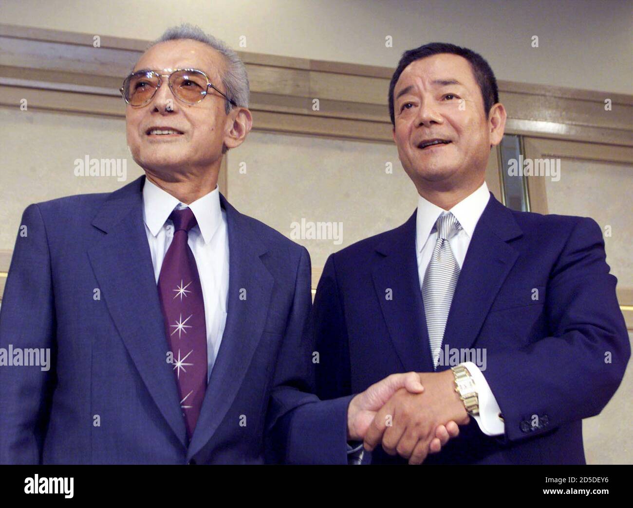 Japanese game maker Nintendo President Hiroshi Yamauchi (L) and computer  entertainment maker Konami Presidnet Kagemasa Kozuki pose for photographers  at a Tokyo hotel after announcing that they have agreed to establish the