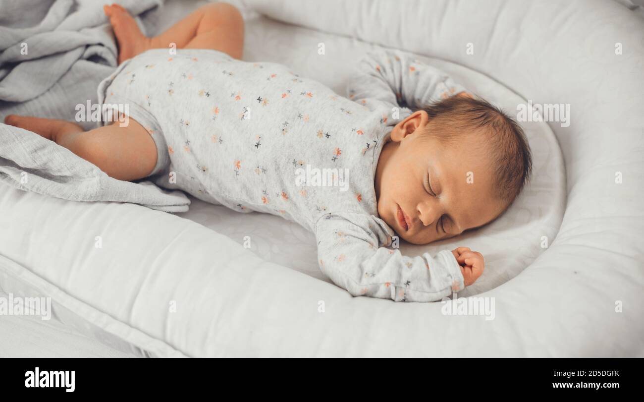 Newborn baby sleeping in safe in her bed on a white blanket at home Stock Photo Alamy