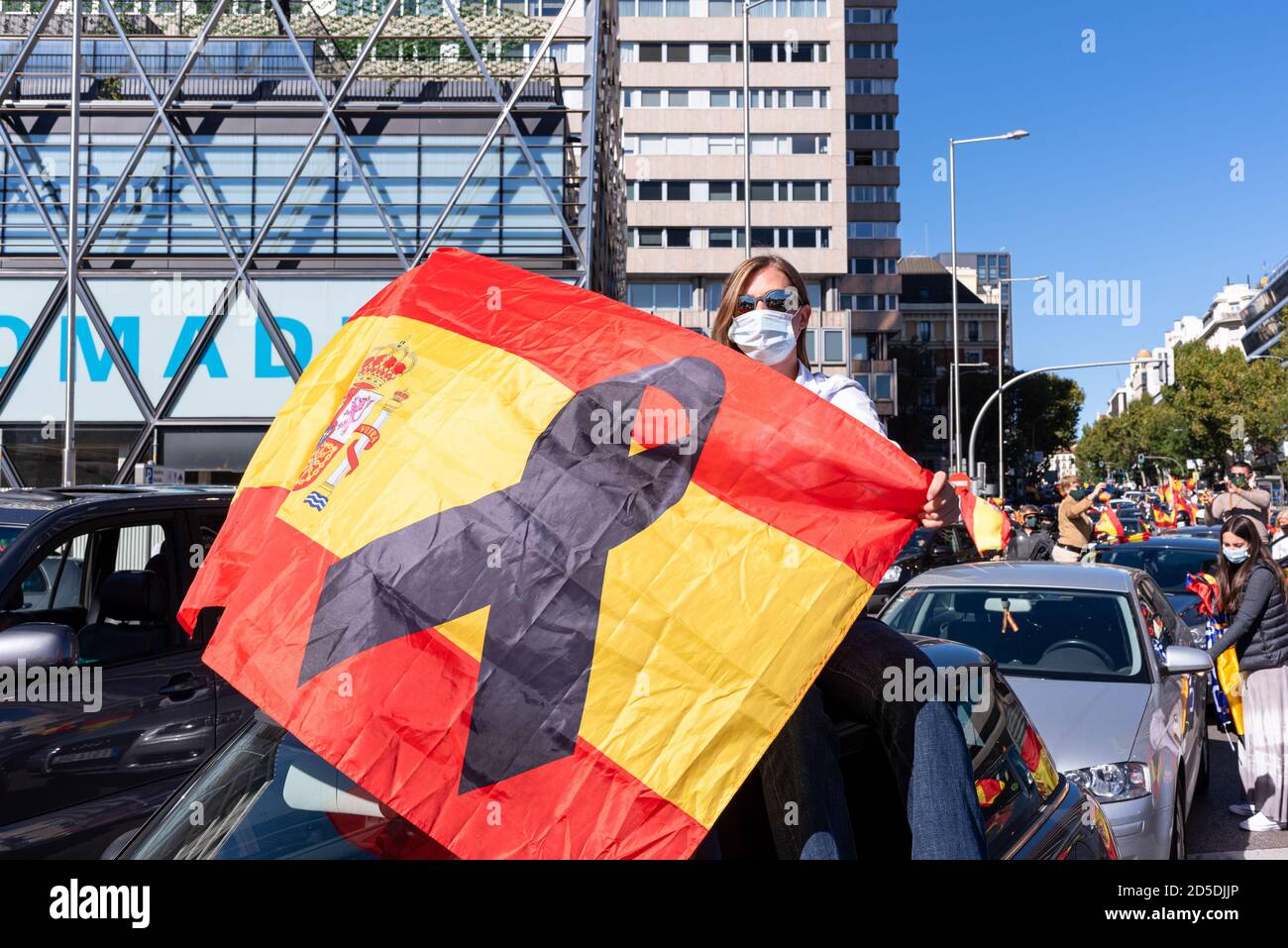 Madrid, Spain, 12th oct 2020.  Young woman wearing mask holding flag as he attends a protest against Spanish government's handling of the COVID-19 cri Stock Photo