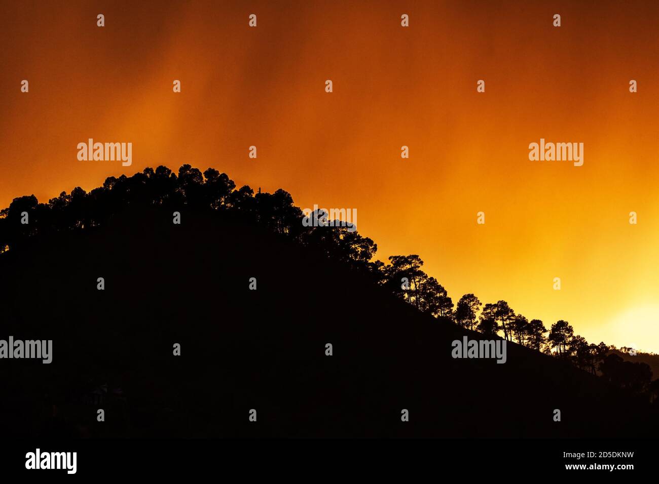 Fiery sky over silhouetted hill Stock Photo