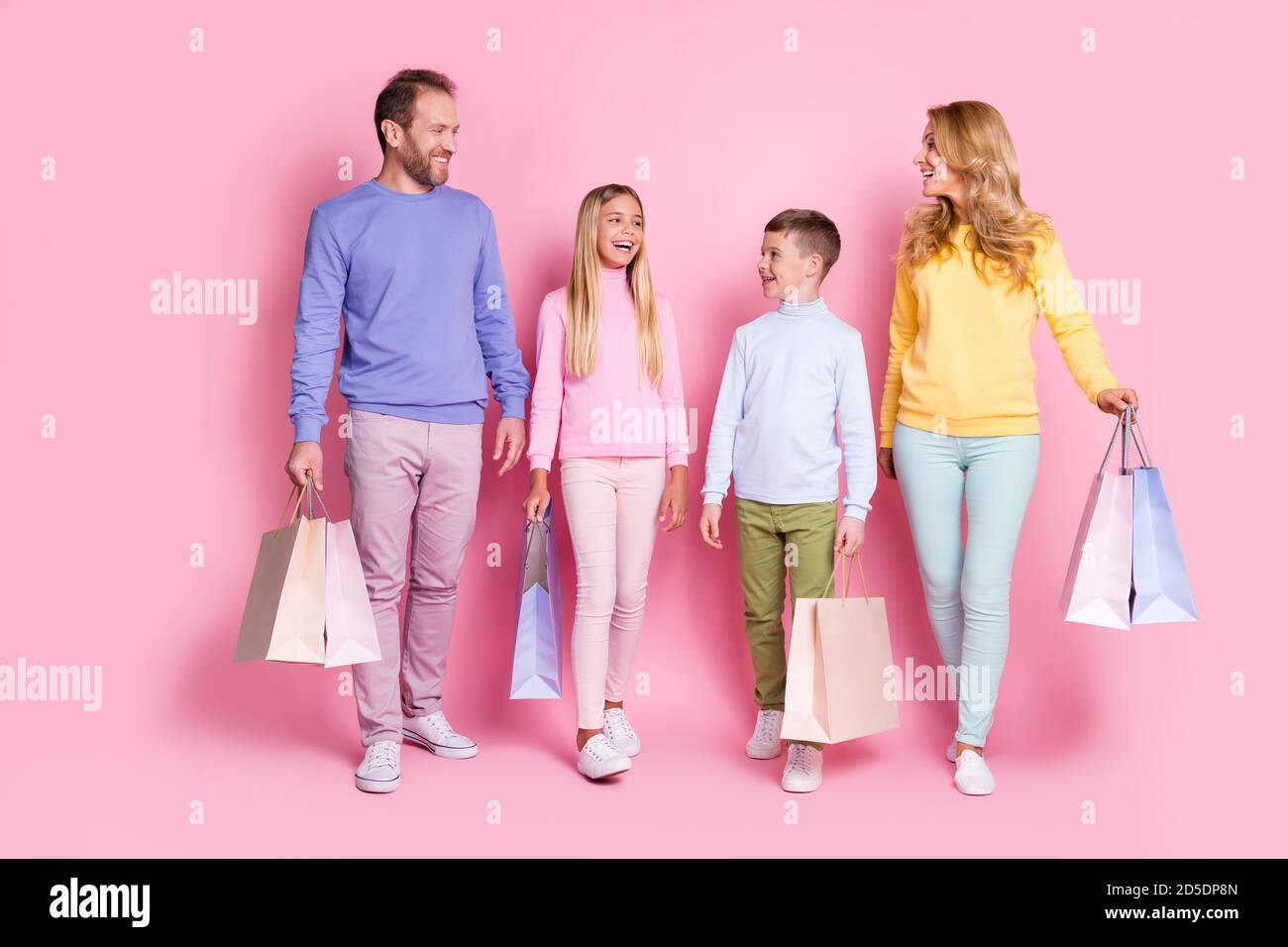 Full length photo of positive people mom mommy dad daddy little kids go with shopping bags isolated on pink color background Stock Photo