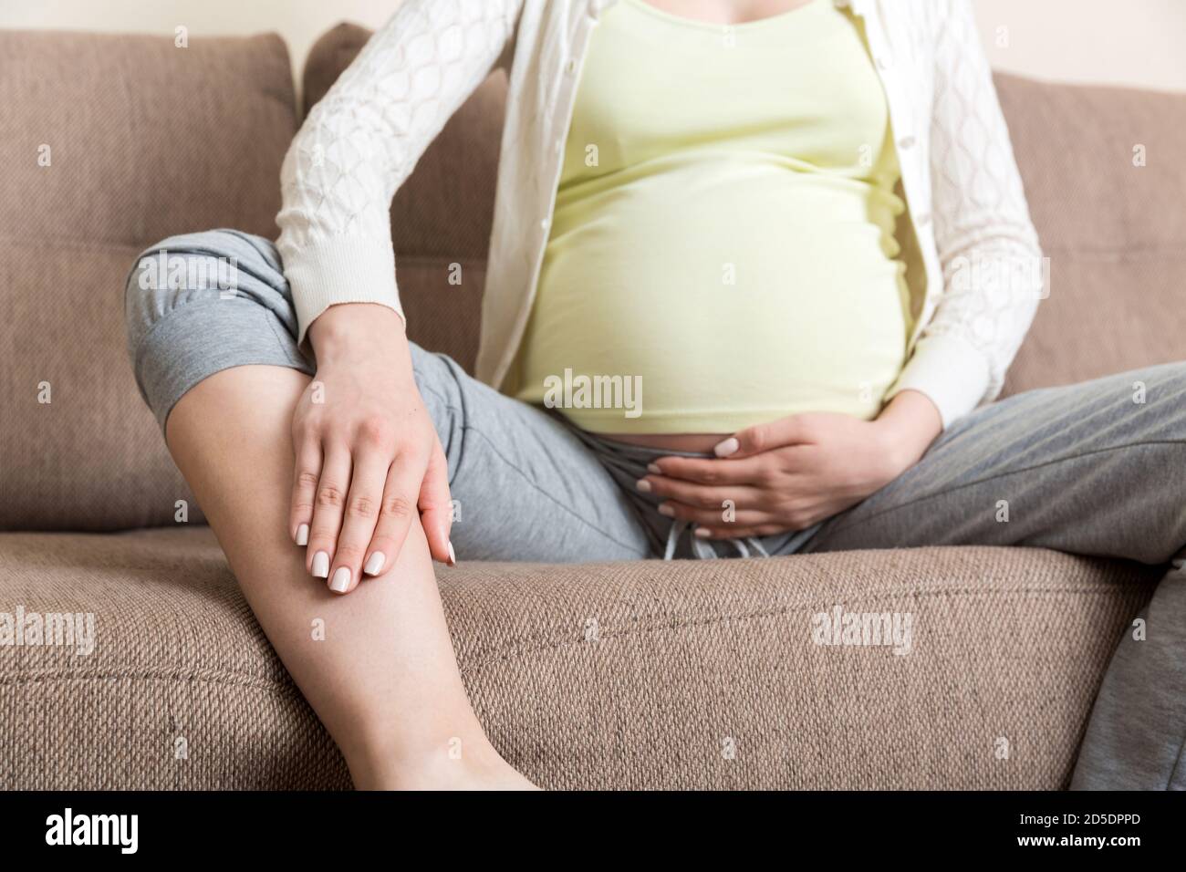Leg cramps during pregnancy. Closeup of hands massaging swollen foot