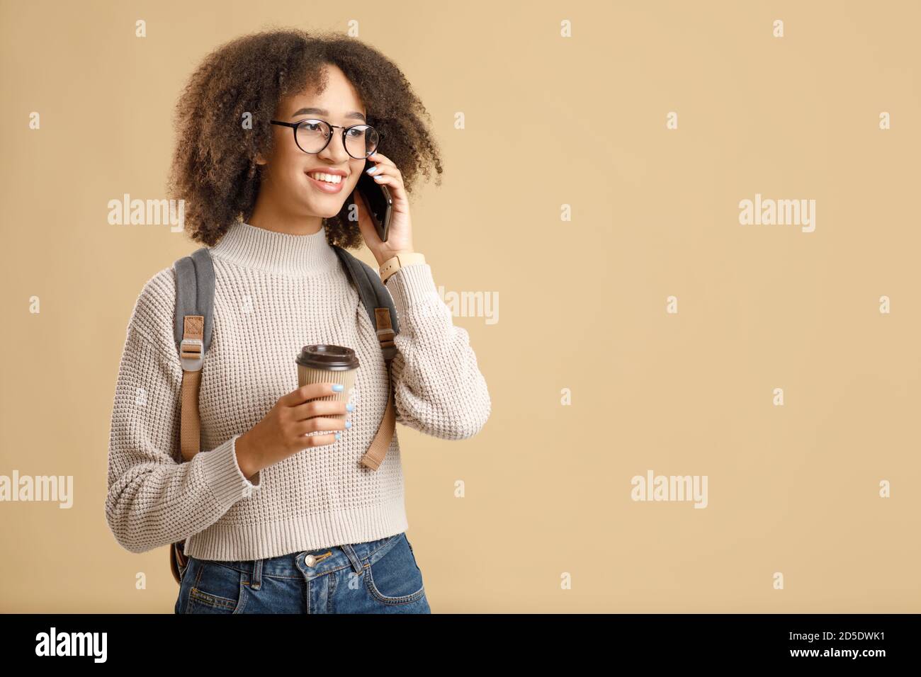 Happy african american lady in glasses with takeaway coffee speaks by phone Stock Photo