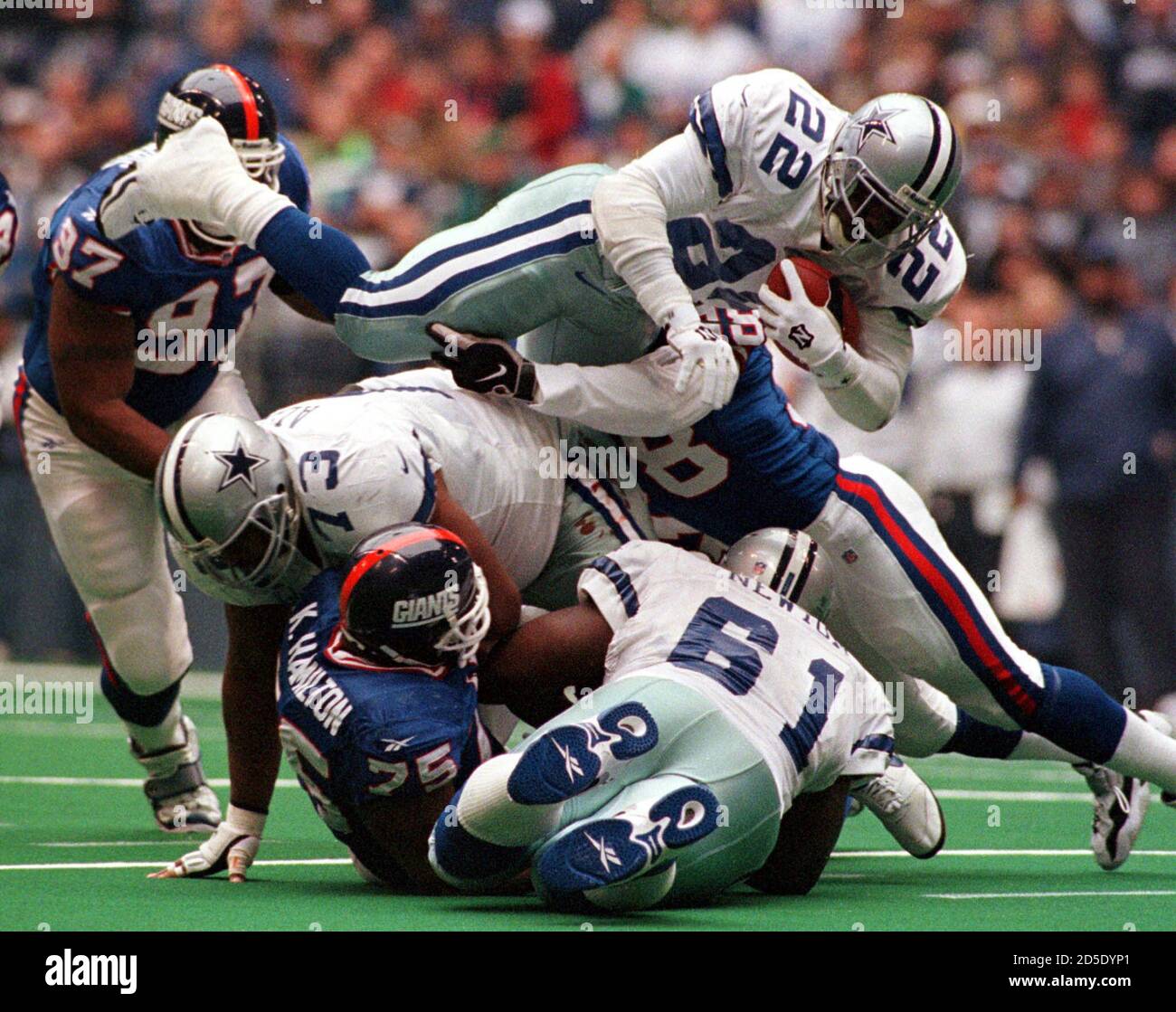 Dallas Cowboys Emmitt Smith takes to the air as New York Giants defenders  Jessie Armstead (R), Robert Harris (97) and Keith Hamilton (75) try to stop  him in the first quarter November