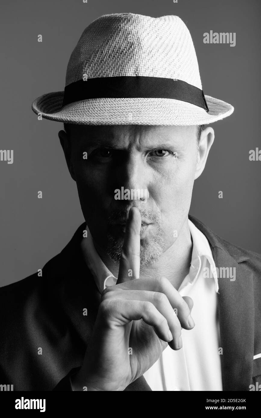 Face of mature businessman with finger on lips Stock Photo