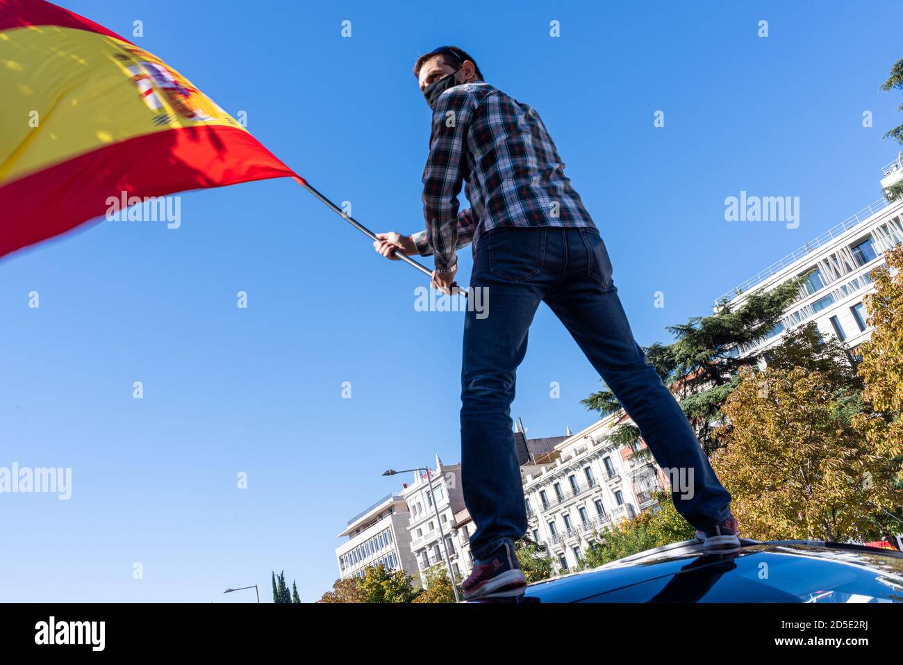 Madrid, Spain, 12th oct 2020.  Man wearing mask waving flag as he attends a protest against Spanish government's handling of the COVID-19 crisis. Stock Photo
