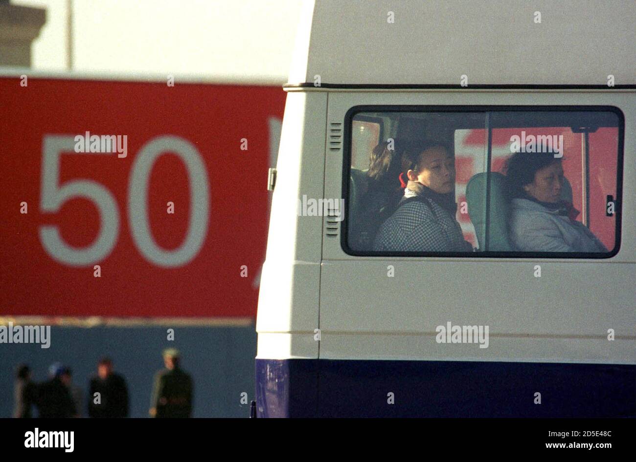 Suspected practitioners of the banned spiritual movement Falun Gong are  detained on a bus in Tiananmen Square in front of a sign celebrating the  50th anniversary of Communist rule in China October