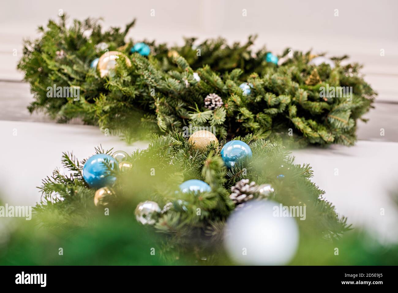 Two Green festive wreaths made of fresh live spruce, decorated with New Year's toys, garlands. Christmas home decoration. Hanging over a fireplace Stock Photo