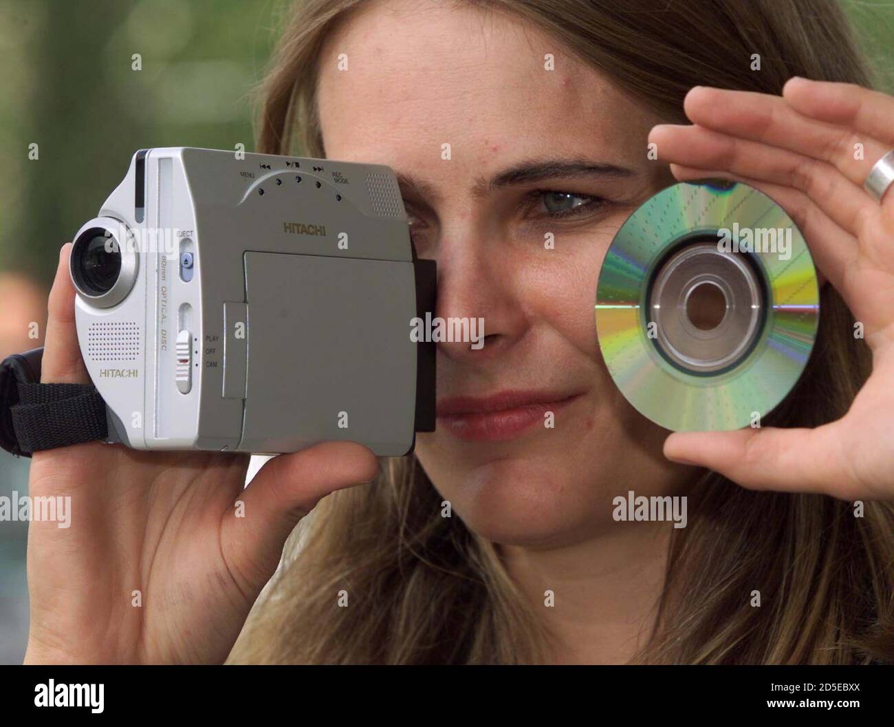 A model looks through a prototype of new Hitatchi DVD Videocamera as she  holds a DVD disc (Digital Versatile Disc) presented as world premier of  Japanese company Hitachi at the world's largest