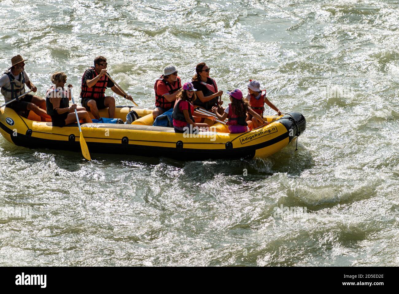 Rafting on white water, a group of people, children and adults, with an instructor on an inflatable raft in the River Adige in Verona downtown, Italy. Stock Photo