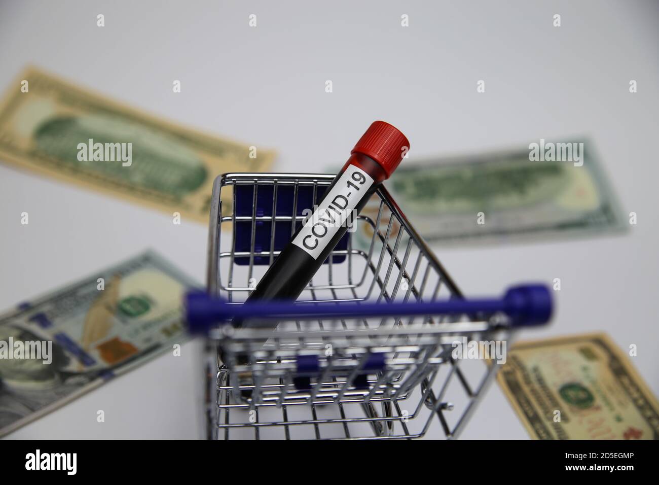 View on modell of shopping cart with covid-19 blood sample tube and us dollar bills background  -consumer behaviour and retail  trade during corona cr Stock Photo