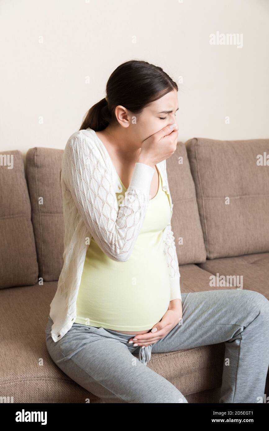 Pregnancy Morning Sickness. Pregnant Woman Having Nausea Feeling Bad in Sofa at the Home. Stock Photo