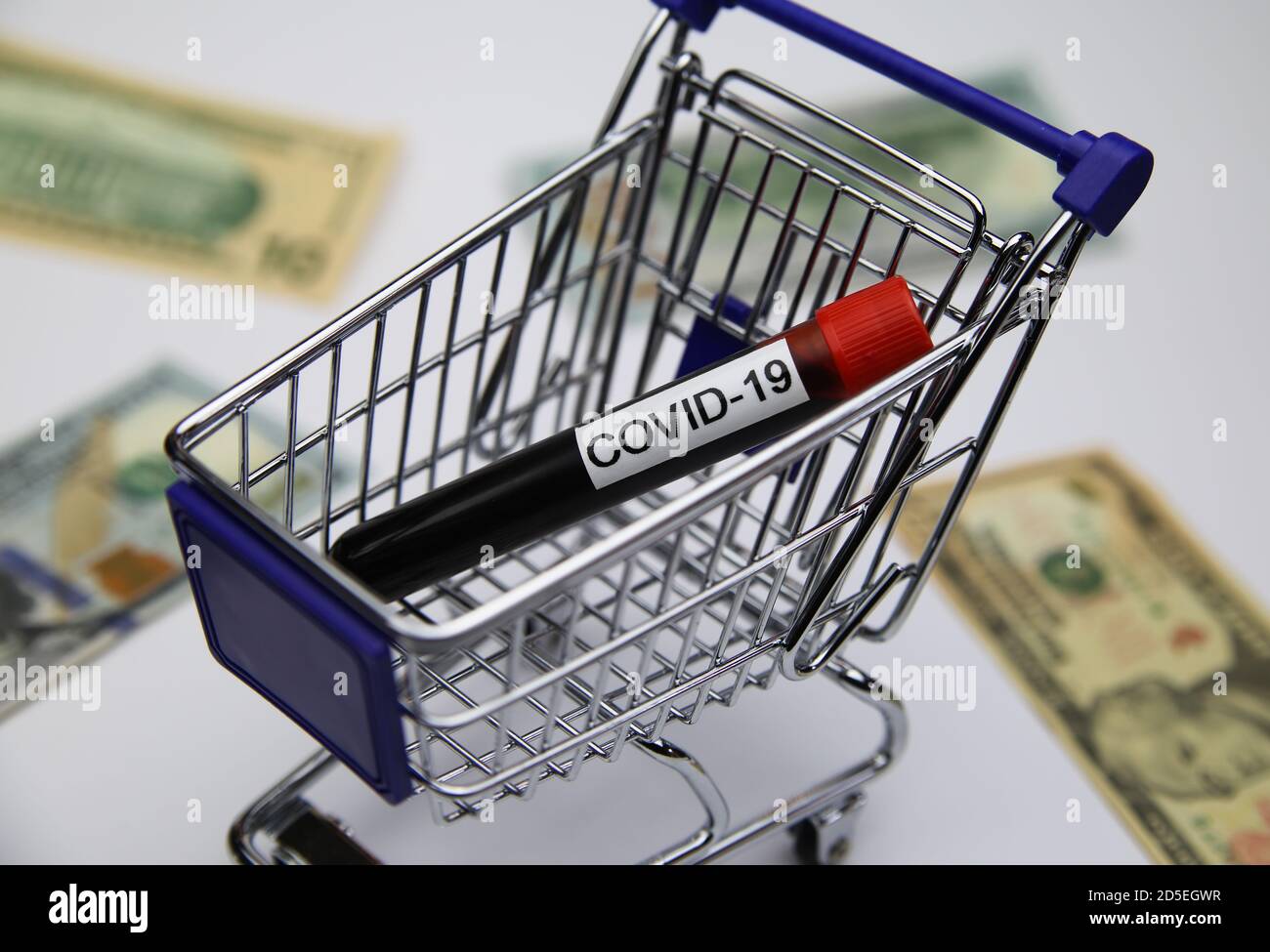 View on modell of shopping cart with covid-19 blood sample tube and us dollar bills background  -consumer behaviour and retail  trade during corona cr Stock Photo