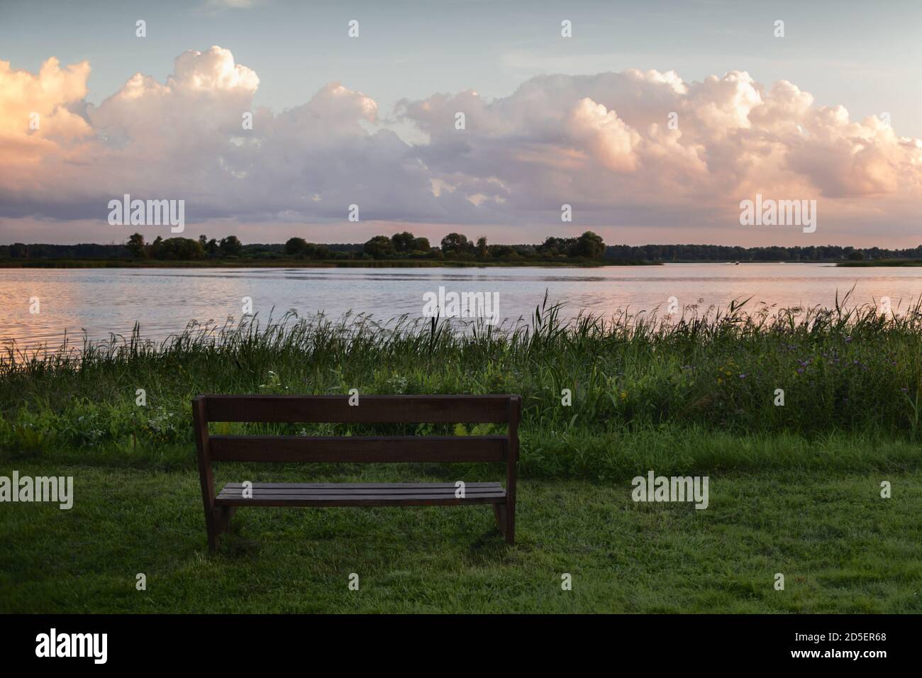 Bench by the lake at sunset overlooking beautiful clouds on a summer evening Stock Photo