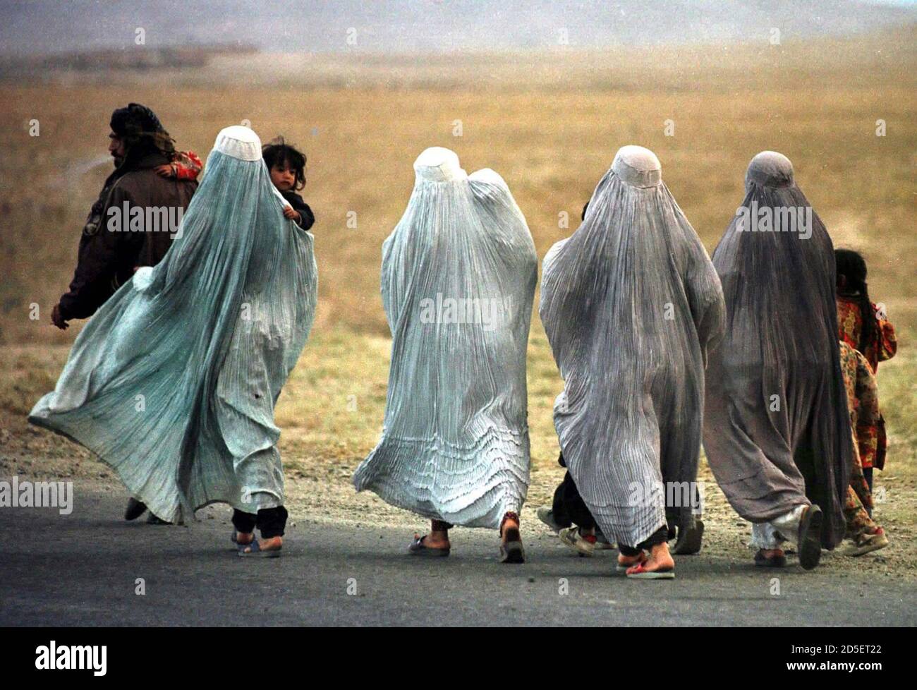 Afghan refugees walk along the road fleeing fighting north of Kabul October 12. Stock Photo
