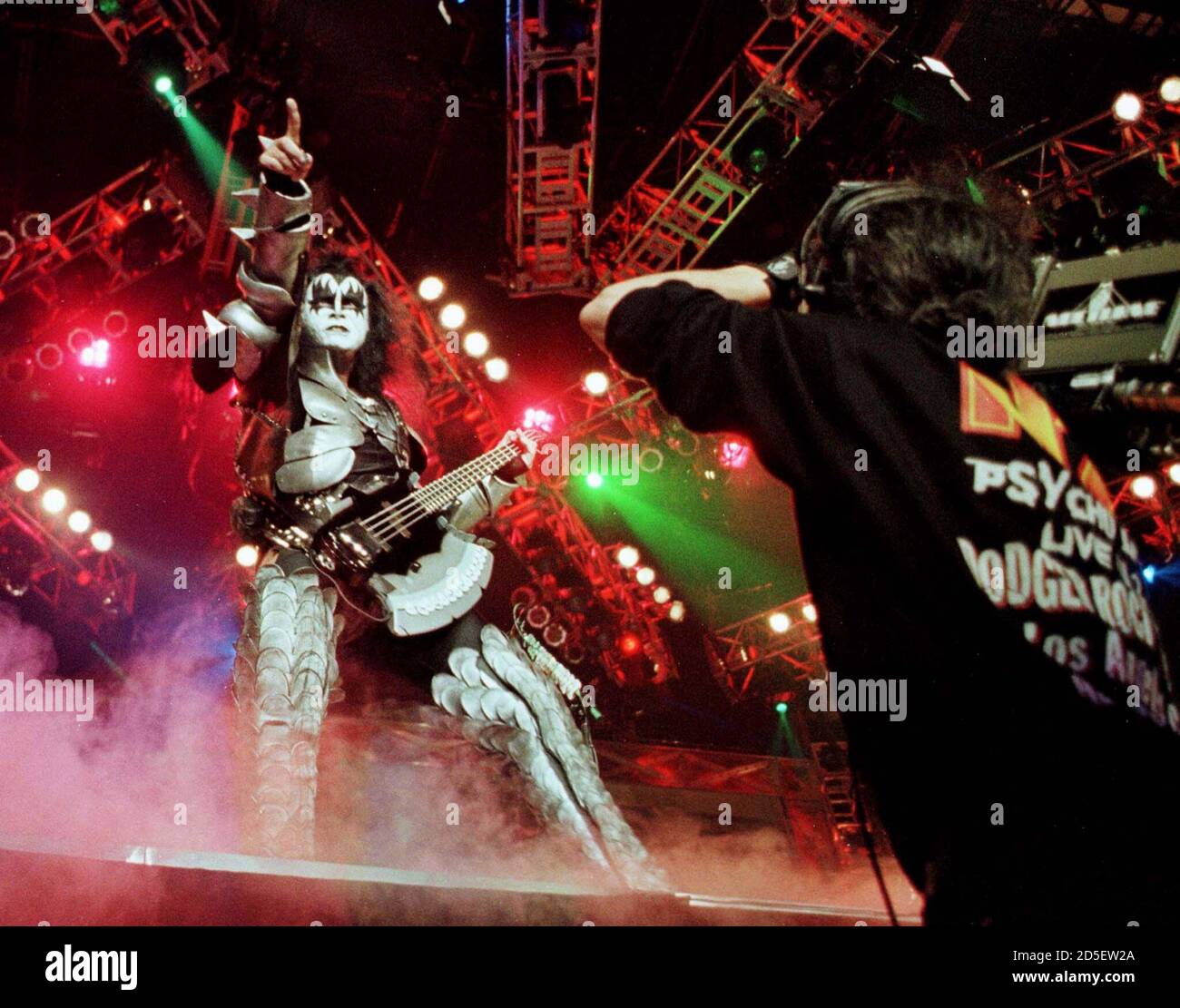 Gene Simmons of the rock group "KISS" performs as a video cameraman records  during a live television broadcast of the band's Halloween concert October  31 in Los Angeles. The band kicked off