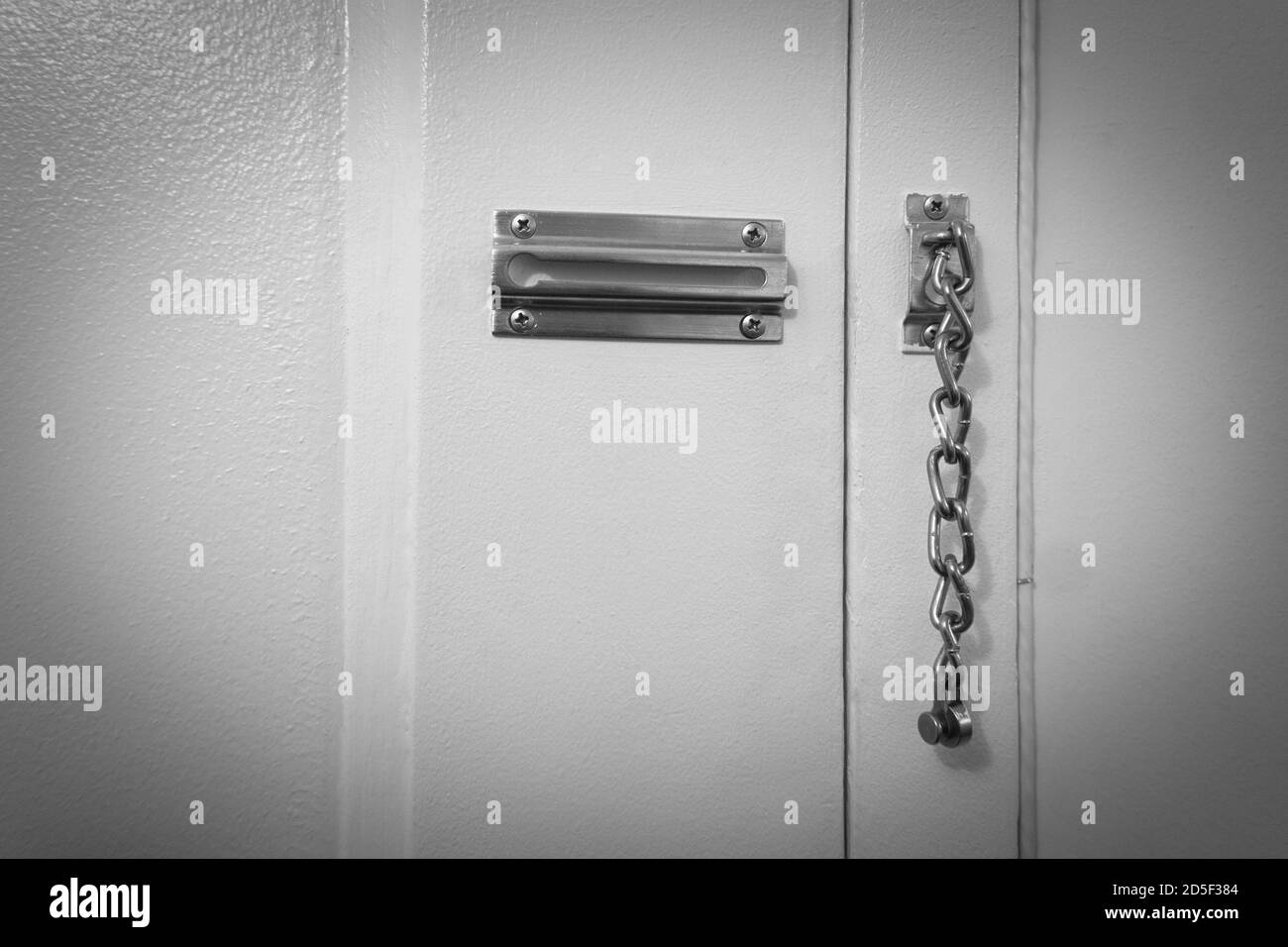 Door chain attached to a white door as a security measures Stock Photo