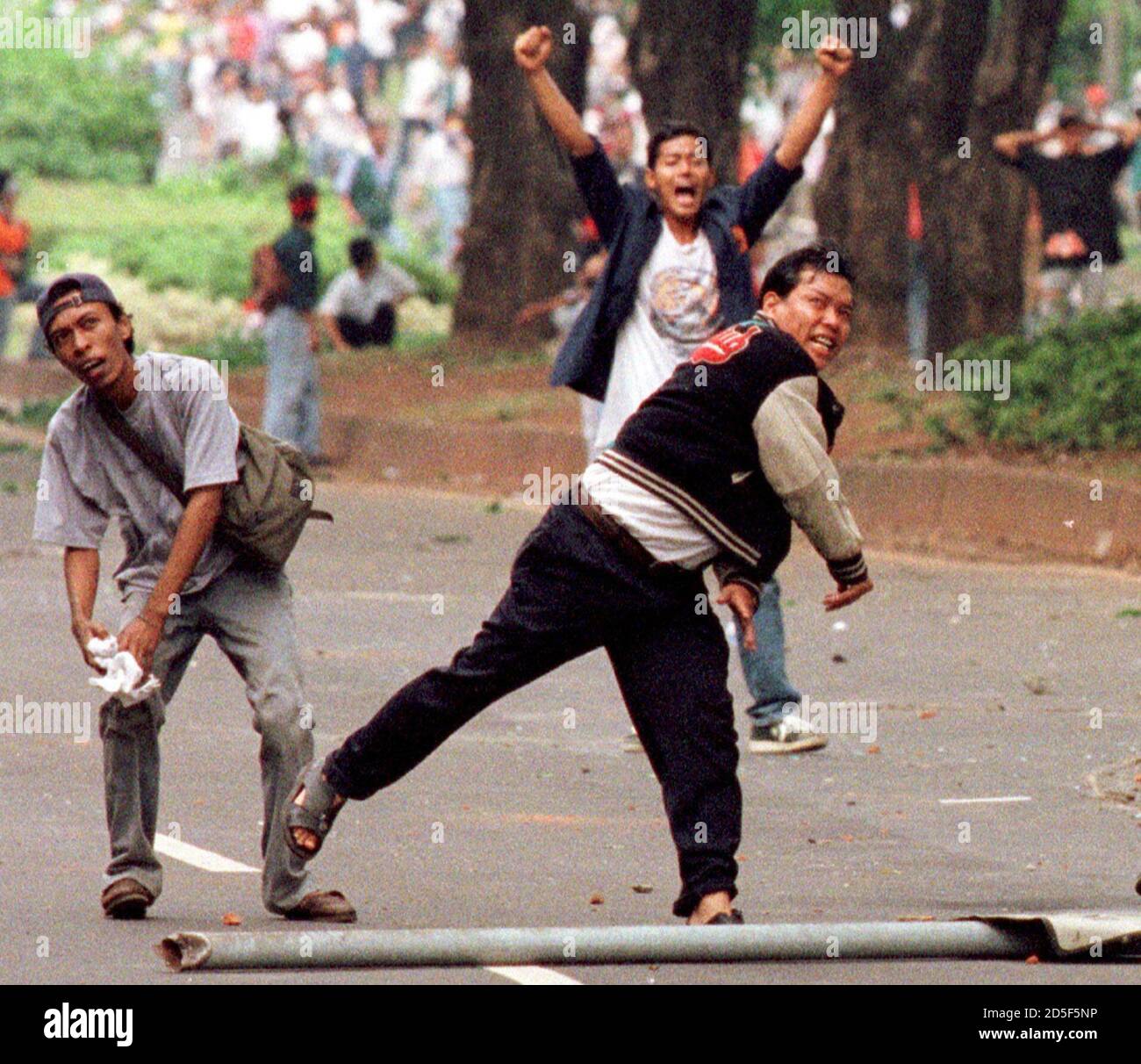 Indonesian anti-government protestors hurl stones at police forces on Jakarta's main street November 13. Troops fired rubber bullets, teargas and bursts from water cannon to disperse thousands of students and anti-government protesters demanding more political reform. Five people were killed and scores have been injured while the People's Consultative Assembly (MPR) was holding the last day of a four-day session to decide on the country's political future. Stock Photo