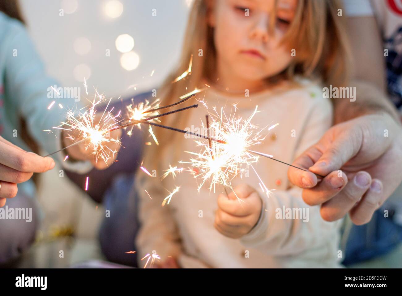 Happy family light sparklers, have fun, fool around on the background of  yellow garlands of lights and bokeh Christmas tree branches. Good New Year  sp Stock Photo - Alamy