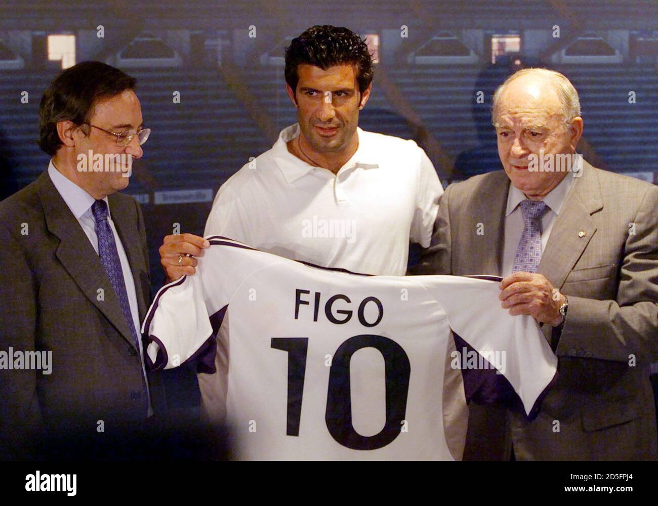 Portuguese player Luis Figo holds the Real Madrid shirt along with club  President Florentino Perez (L) and soccer legend Alfredo Di'Stefano (R) at  his presentation in Bernabeu stadium July 24. Figo, who