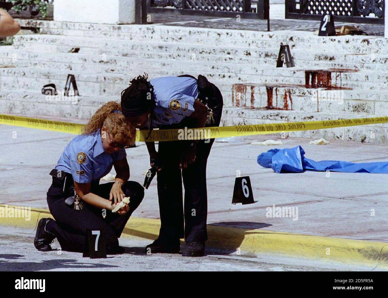 With the blood-stained steps of fashion designer Gianni Versace Miami Beach  mansion in the background police investigators look for evidence at the  murder scene of Versace July 15. Versace was shot twice