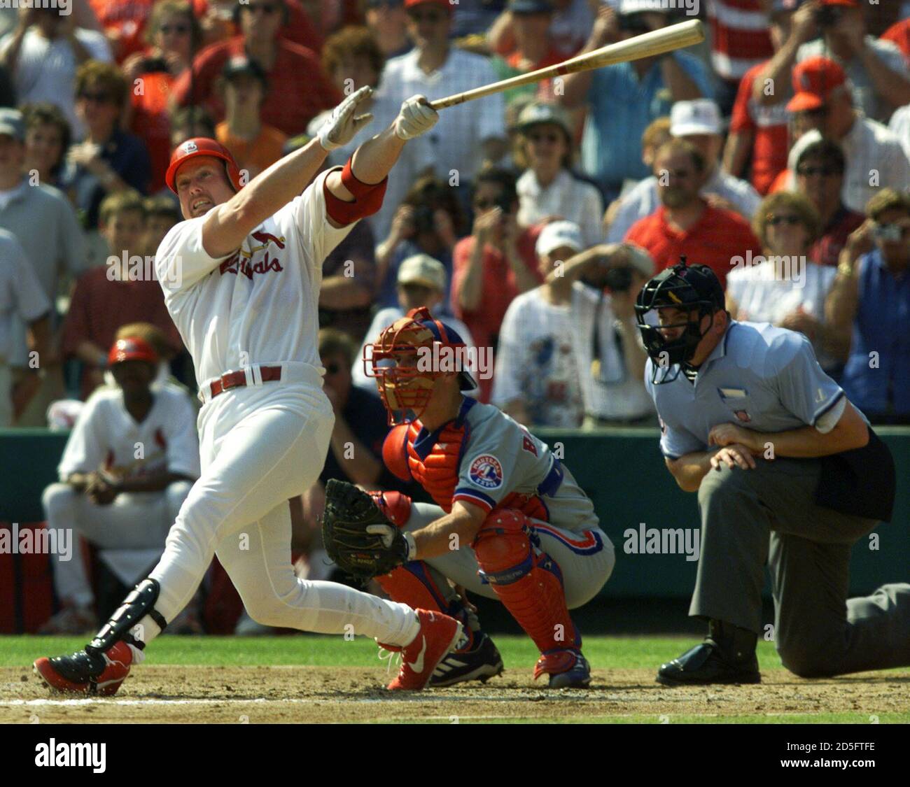 St. Louis Cardinals Mark McGwire hits his 69th home run of the year in  front of Montreal Expos catcher Michael Barrett and umpire Rich Rieker in  the third inning of their game