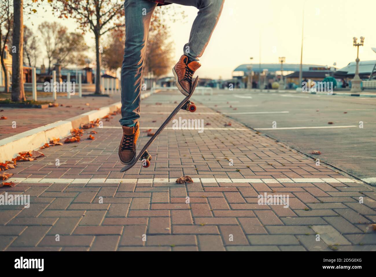 Skateboarding. A man does an Ollie stunt on a skateboard. Board in the air. Close-up of legs. Stock Photo