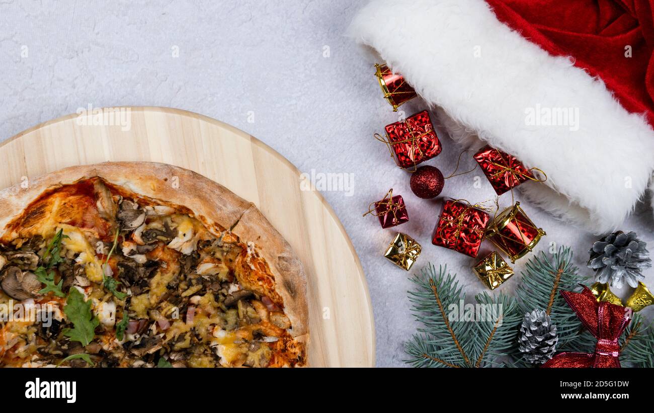 Flat lay of pizza spinning 360 degree rotation on wooden salver, Christmas decorations around. Concept of discount and promotion in a pizzeria. Copy s Stock Photo