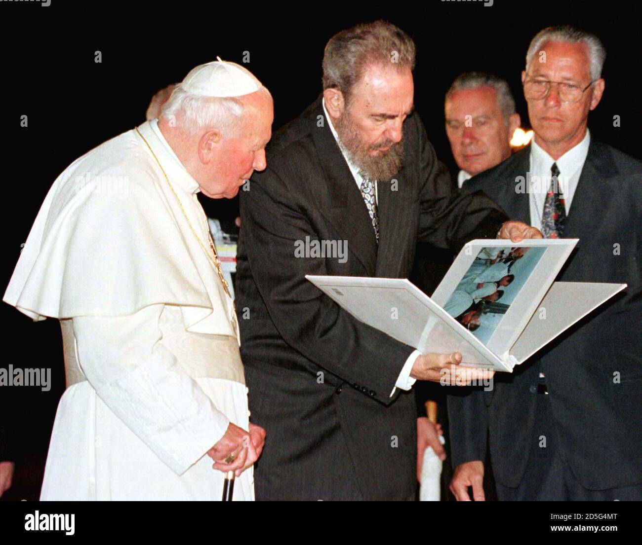 Cuban President Fidel Castro (C) shows Pope John Paul II a photo album  documenting his trip to Cuba during departure ceremonies in Havana January  25. Castro presented the Pontiff with the album